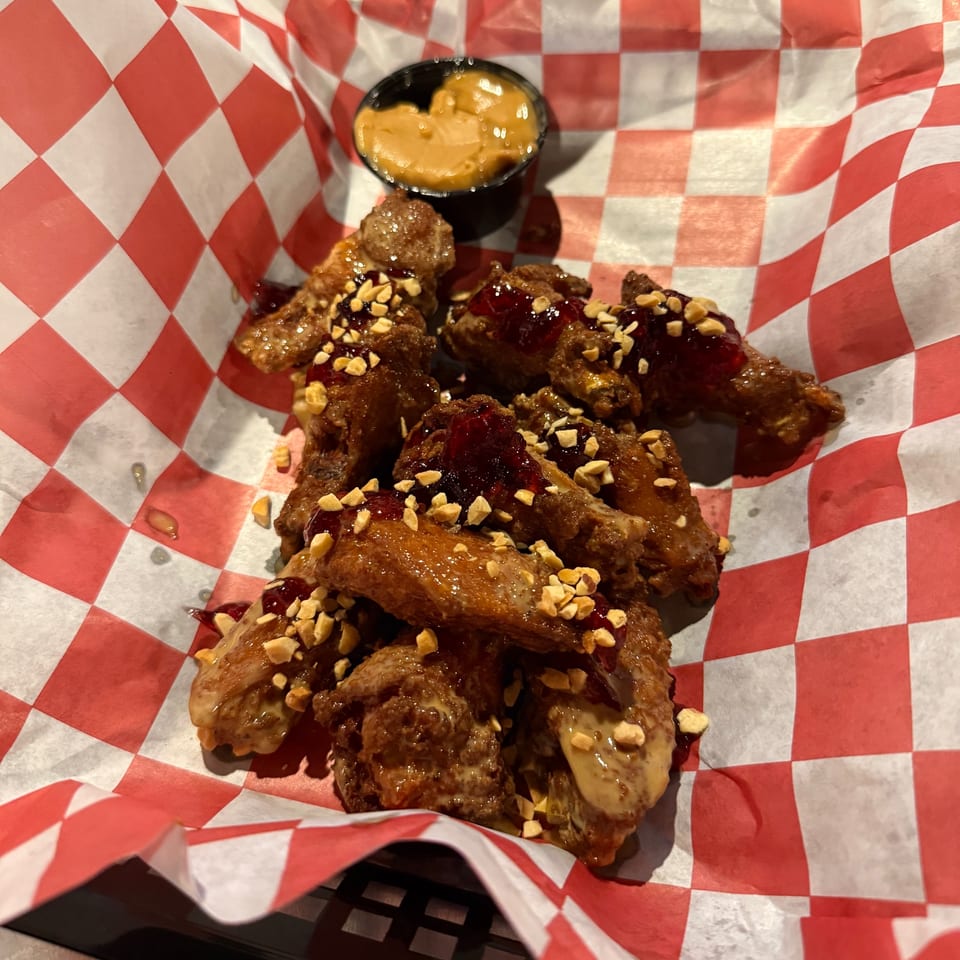 Pitchers Pub's peanut butter and jelly wings with chopped peanuts and a side of peanut sauce.